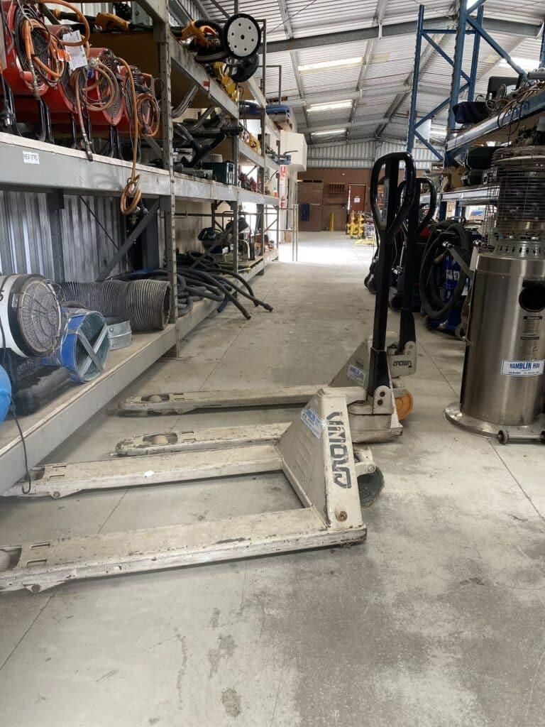 A Pallet Truck is Parked in a Warehouse Next to Shelves — Hamblin Hire in Albury, NSW