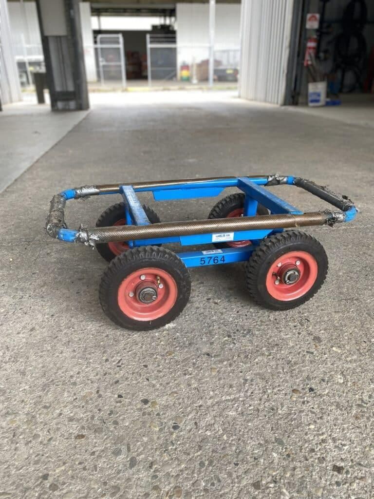 A Blue Cart With Red Wheels is Sitting on the Ground — Hamblin Hire in Albury, NSW