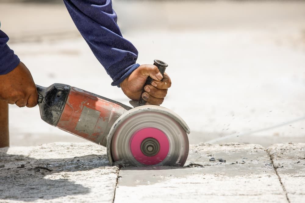 A Man is Using a Circular Saw to Cut Concrete — Hamblin Hire in Albury, NSW