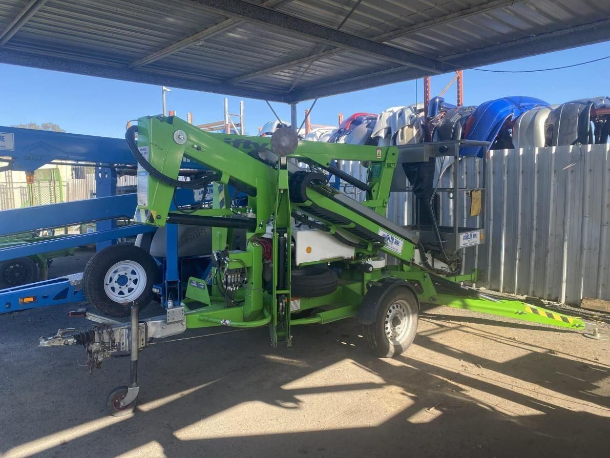 A Green Aerial Lift is Parked Under a Canopy in a Parking Lot — Hamblin Hire in Albury, NSW