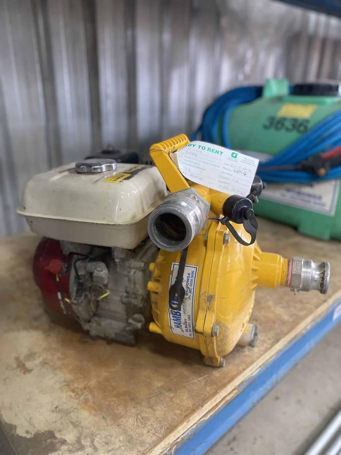 A Yellow Water Pump is Sitting on Top of a Wooden Table — Hamblin Hire in Albury, NSW