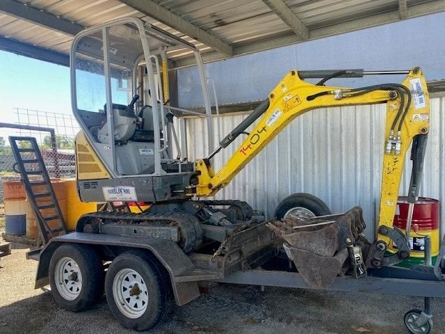 A Yellow Excavator is Parked on a Trailer Under a Roof — Hamblin Hire in Albury, NSW