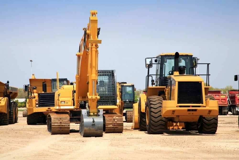 A Row of Yellow Construction Vehicles Are Parked in a Dirt Lot — Hamblin Hire in Albury, NSW