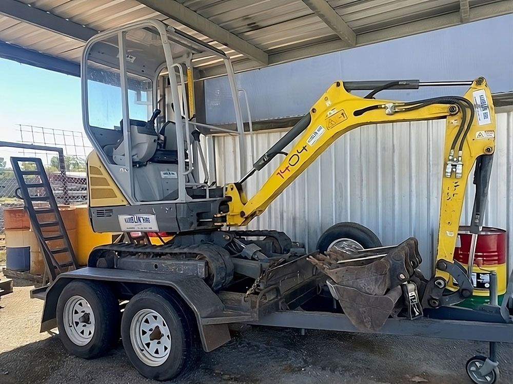 A Yellow Excavator is Parked on a Trailer in Front of a Building — Hamblin Hire in Albury, NSW