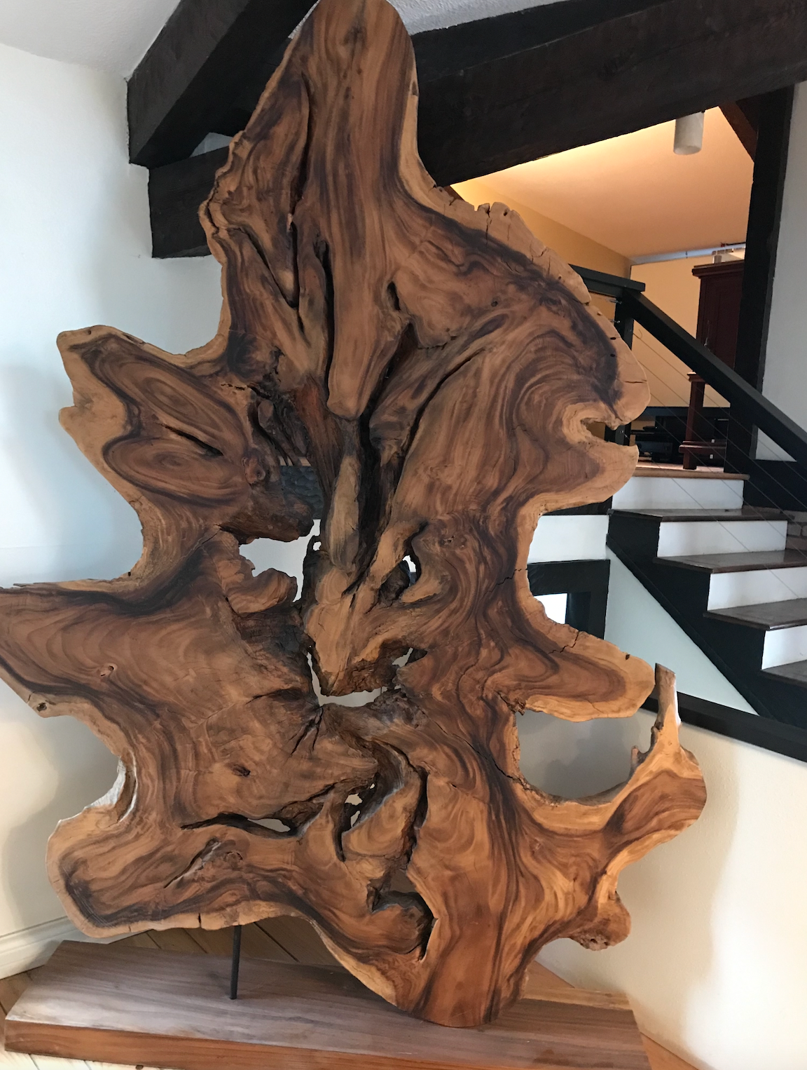 A large piece of wood is sitting on a table in front of a staircase.