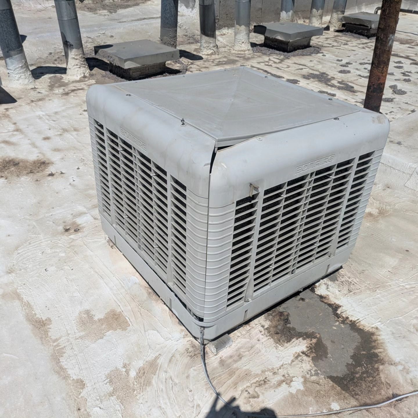 Cooler unit on a flat roof with vents and pipes.