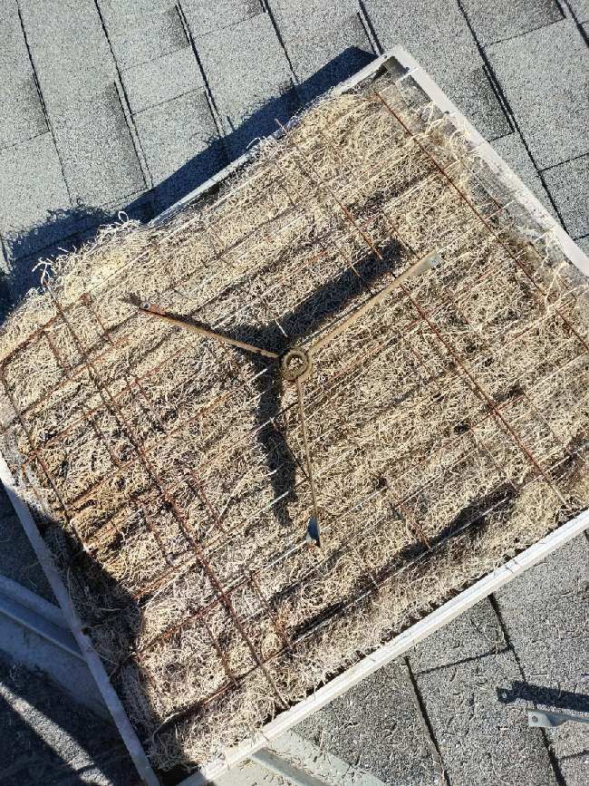 A swamp cooler pad on a rooftop, made of straw and wire mesh.