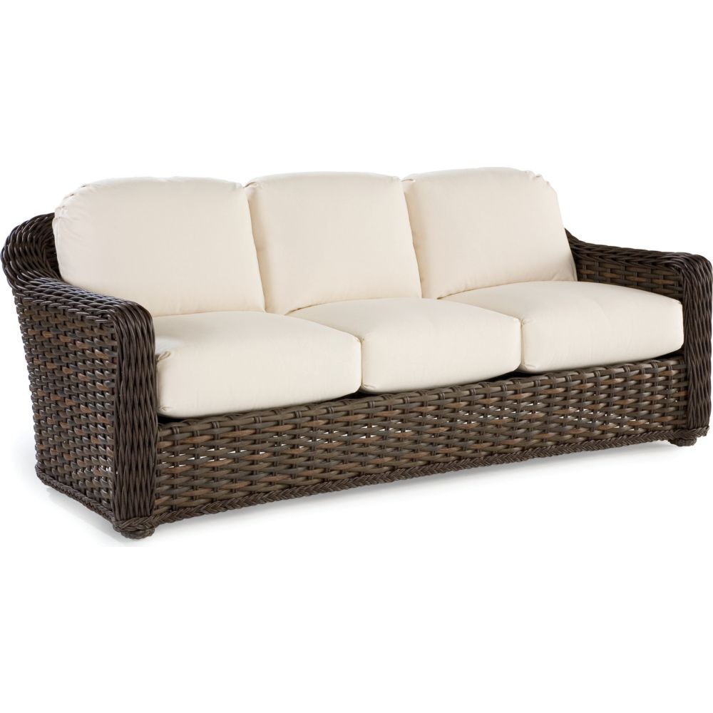 A wicker couch with white cushions on a white background.