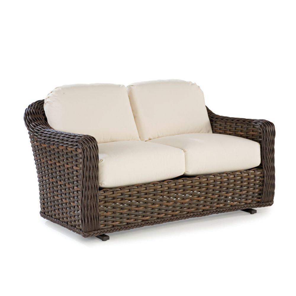 A brown wicker couch with white cushions on a white background.