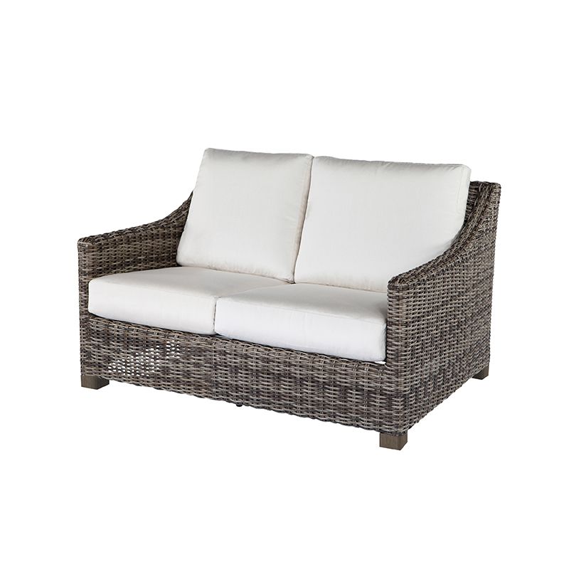 A wicker couch with white cushions on a white background