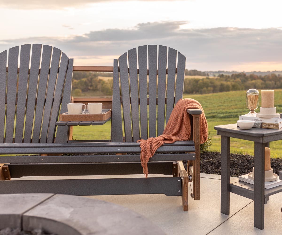 A couple of chairs sitting on top of a concrete patio next to a fire pit.