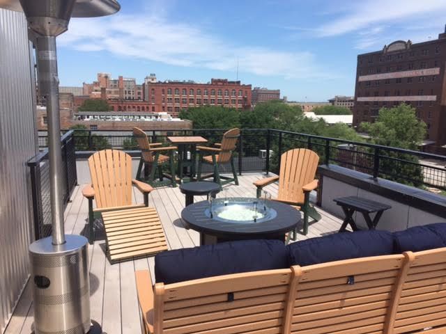 A rooftop deck with chairs tables and a fire pit