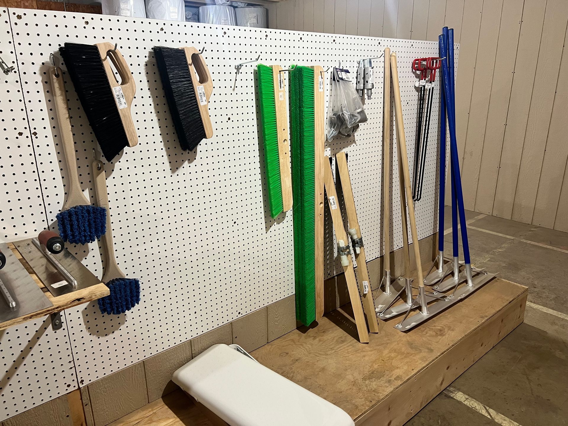 Tools and cleaning supplies hanging on a pegboard in a storage area.
