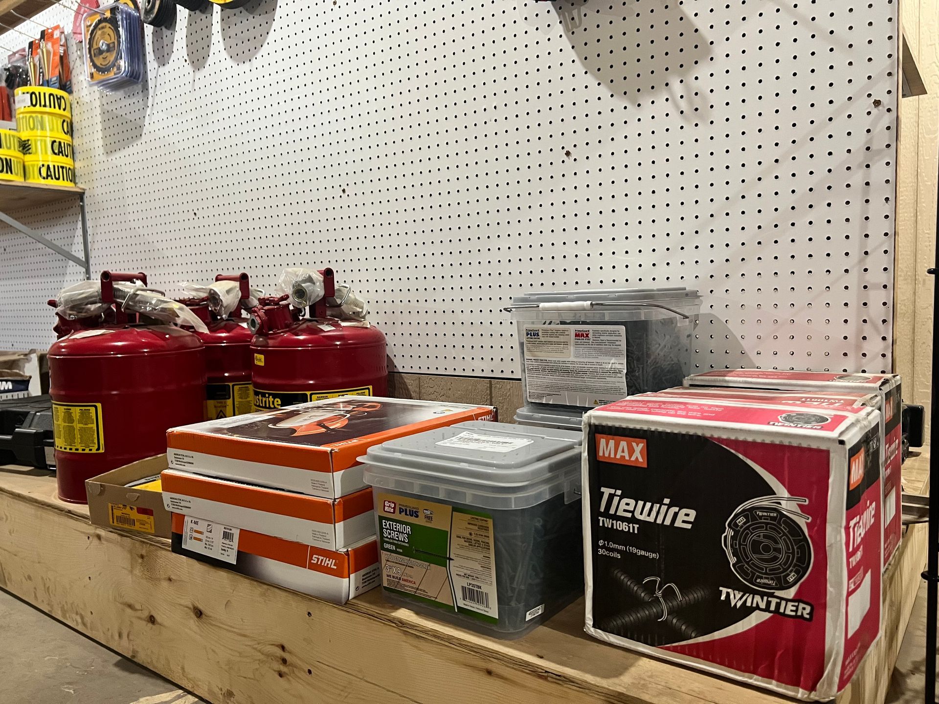 Hardware store shelf with tie wire, tools, and red tanks.
