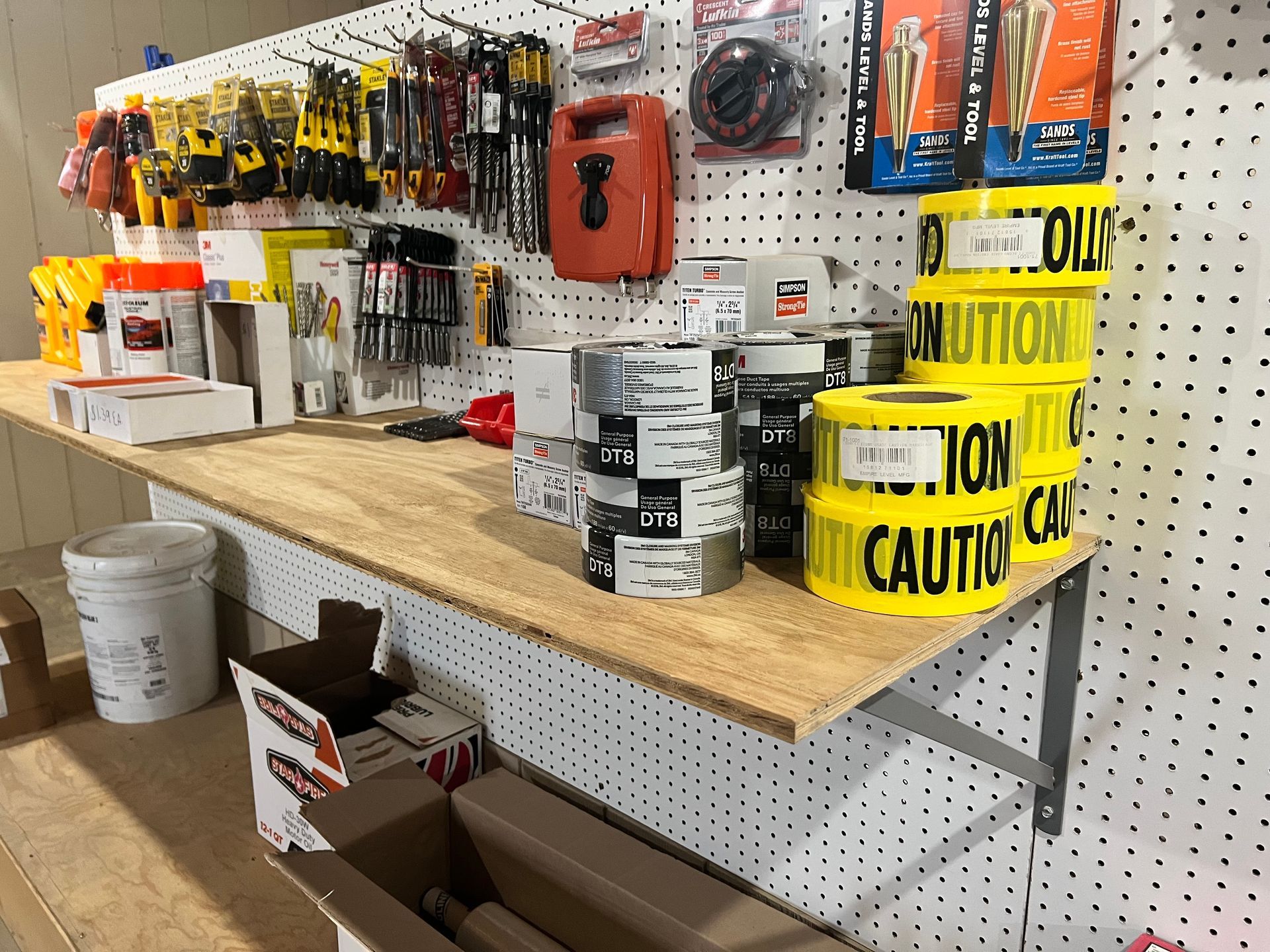 Workbench with tools, caution tape, and supplies displayed on a pegboard wall.