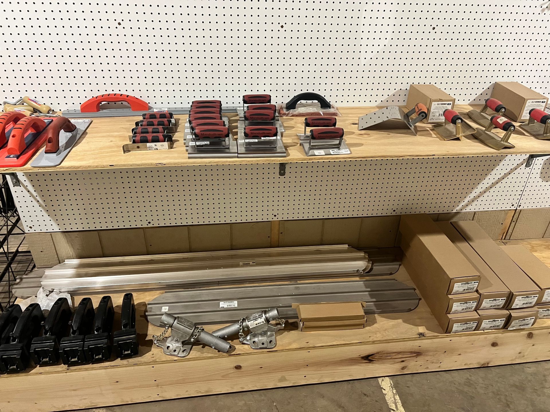 Various hardware parts and tools on a wooden shelf in a workshop setting.