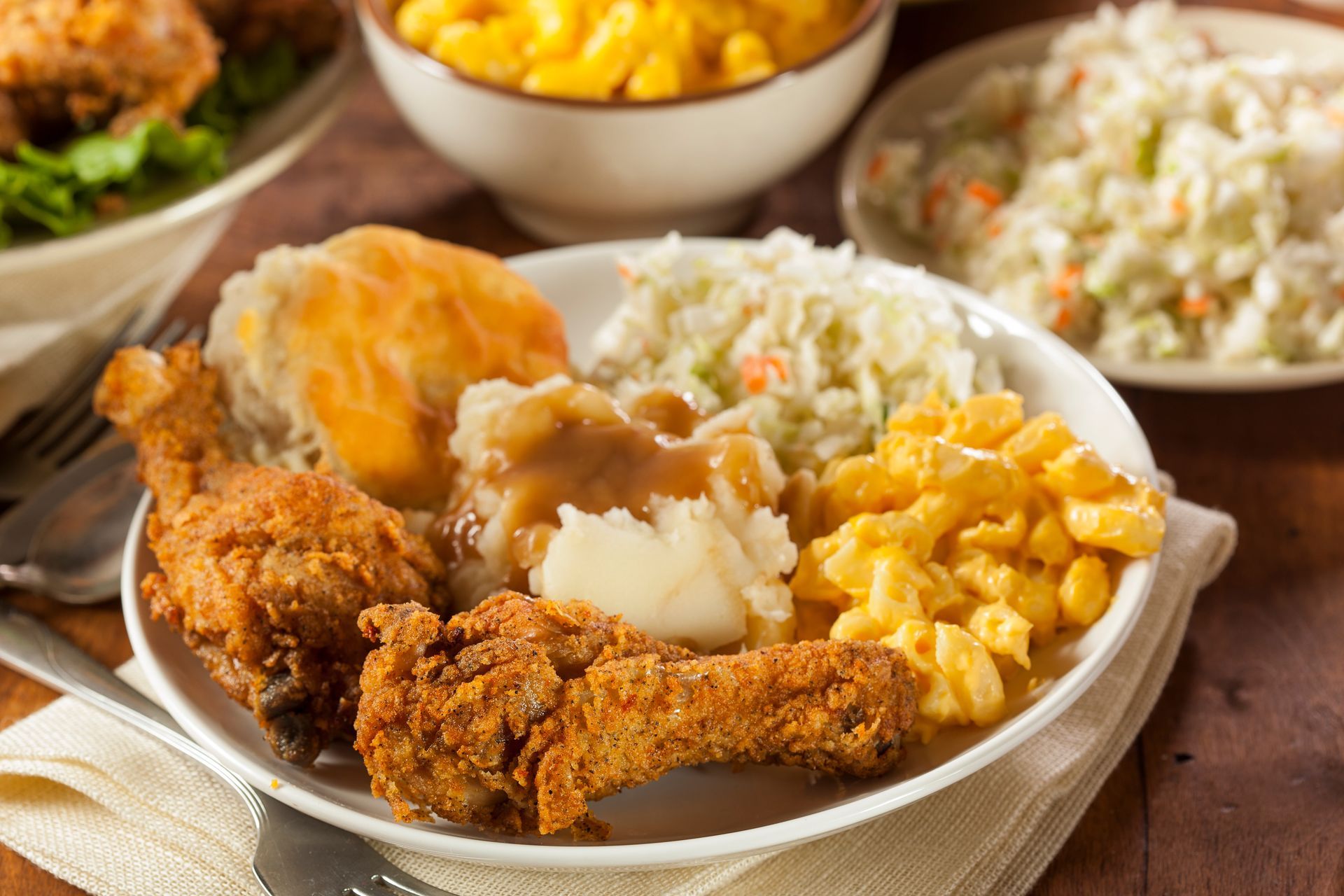 A white plate topped with fried chicken , mashed potatoes , macaroni and cheese , coleslaw and gravy.
