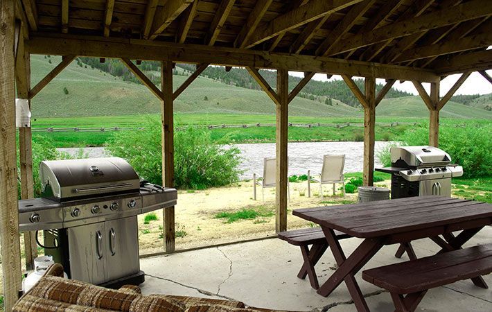 A covered patio with a picnic table and a grill