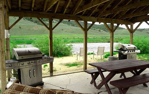 A covered patio with a picnic table and a grill