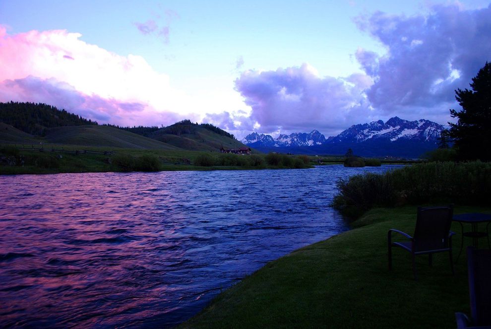 There is a lake in the middle of a field with mountains in the background.