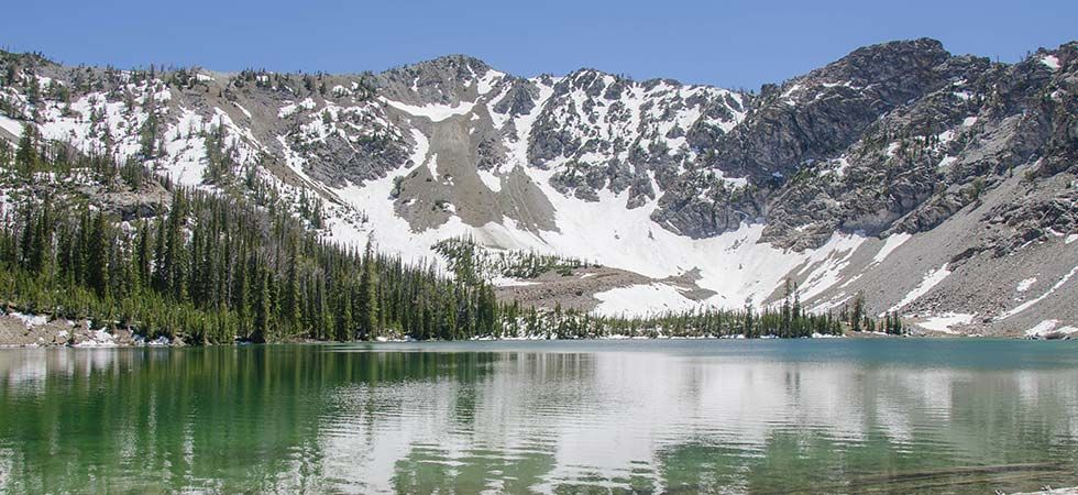 A lake surrounded by snow covered mountains and trees