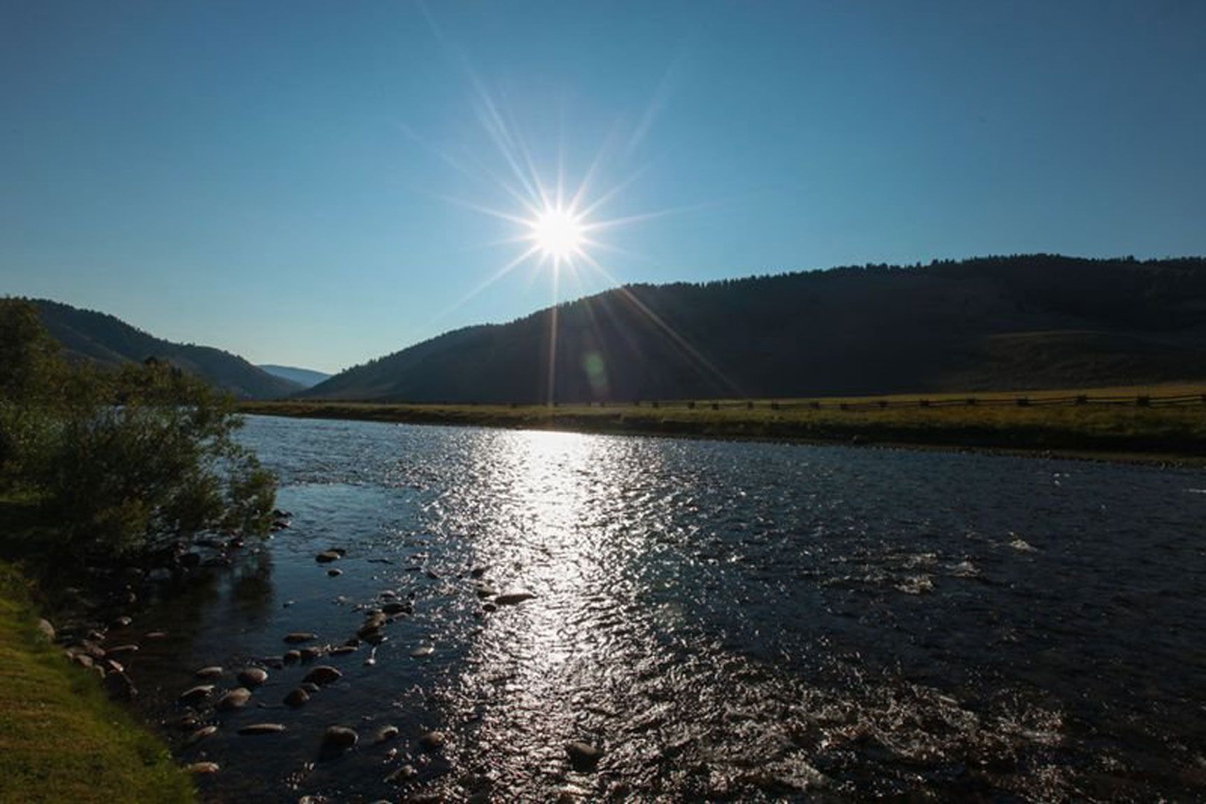 The sun is shining brightly over a river