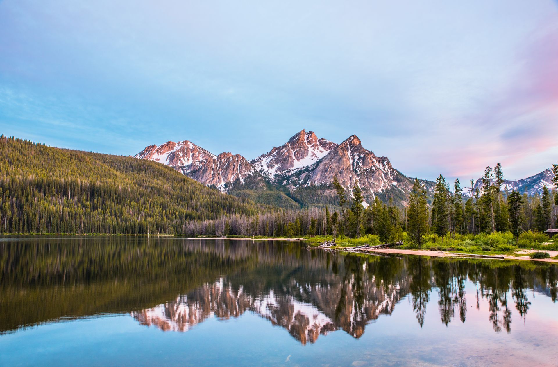 A lake with mountains in the background and trees on the shore.