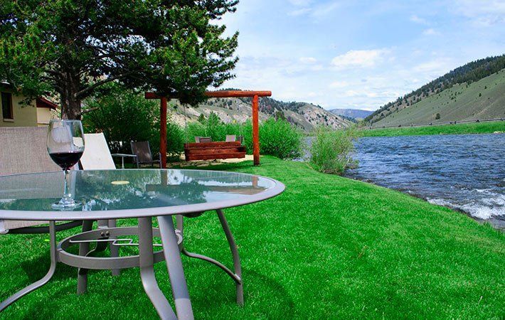 A glass of wine is on a table next to a river.