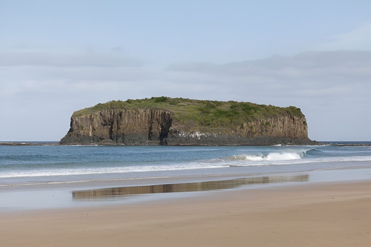 Island Off a Sandy Beach With Waves and a Calm Blue Sky — Dirt Werx in Shellharbour, NSW
