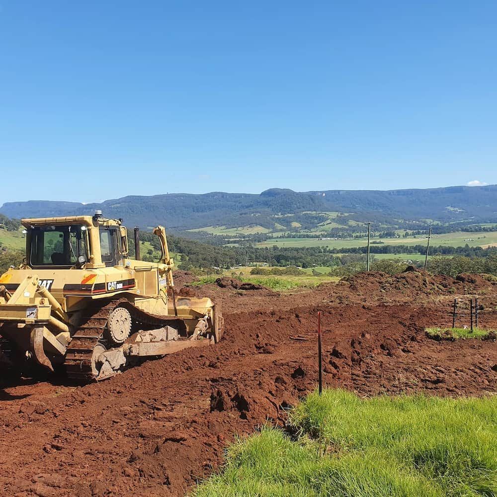 Yellow Bulldozer on a Muddy, Red Earth Site With a Scenic — Dirt Werx in Nowra, NSW
