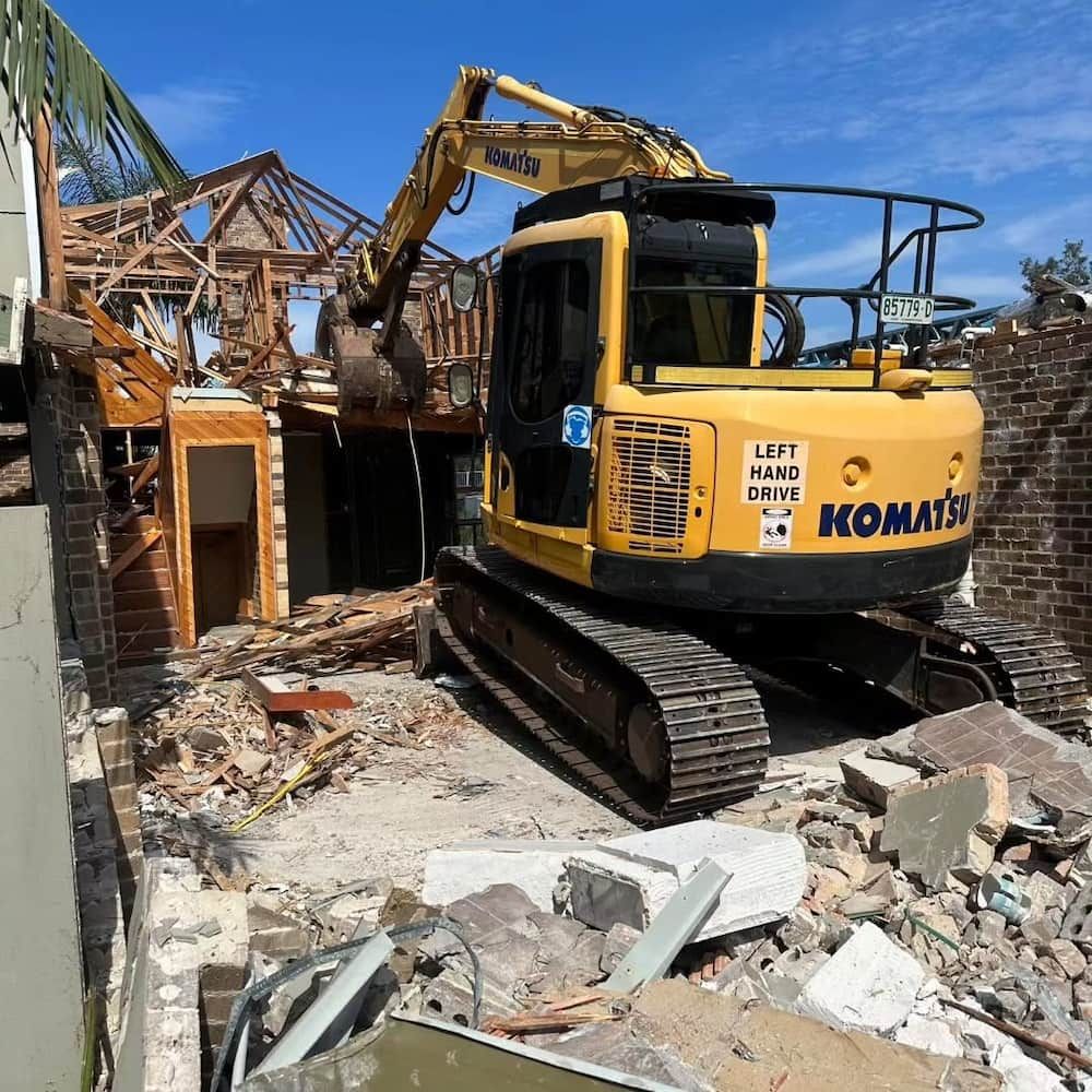 Yellow Komatsu Excavator Demolishing a House — Dirt Werx in Nowra, NSW