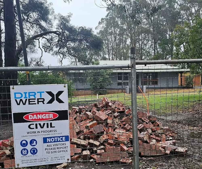 Construction site with a sign, debris, and a house in the background — Dirt Werx in Nowra, NSW