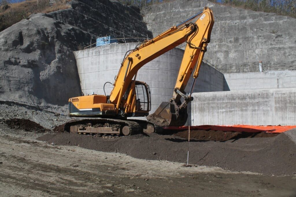 Yellow Excavator Digging in a Construction Site With Concrete Wall — Dirt Werx in Ulladulla, NSW
