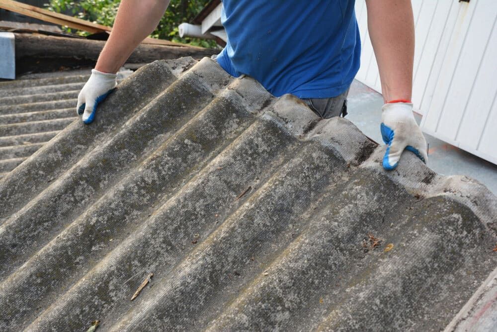 Person in Blue Shirt and Gloves Removing Corrugated Roof Tiles — Dirt Werx in Kiama, NSW