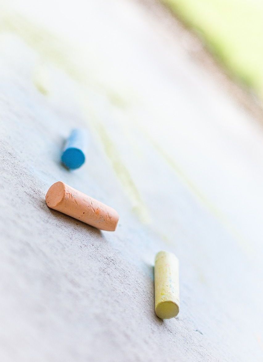 Three different colored chalks are laying on a white surface.