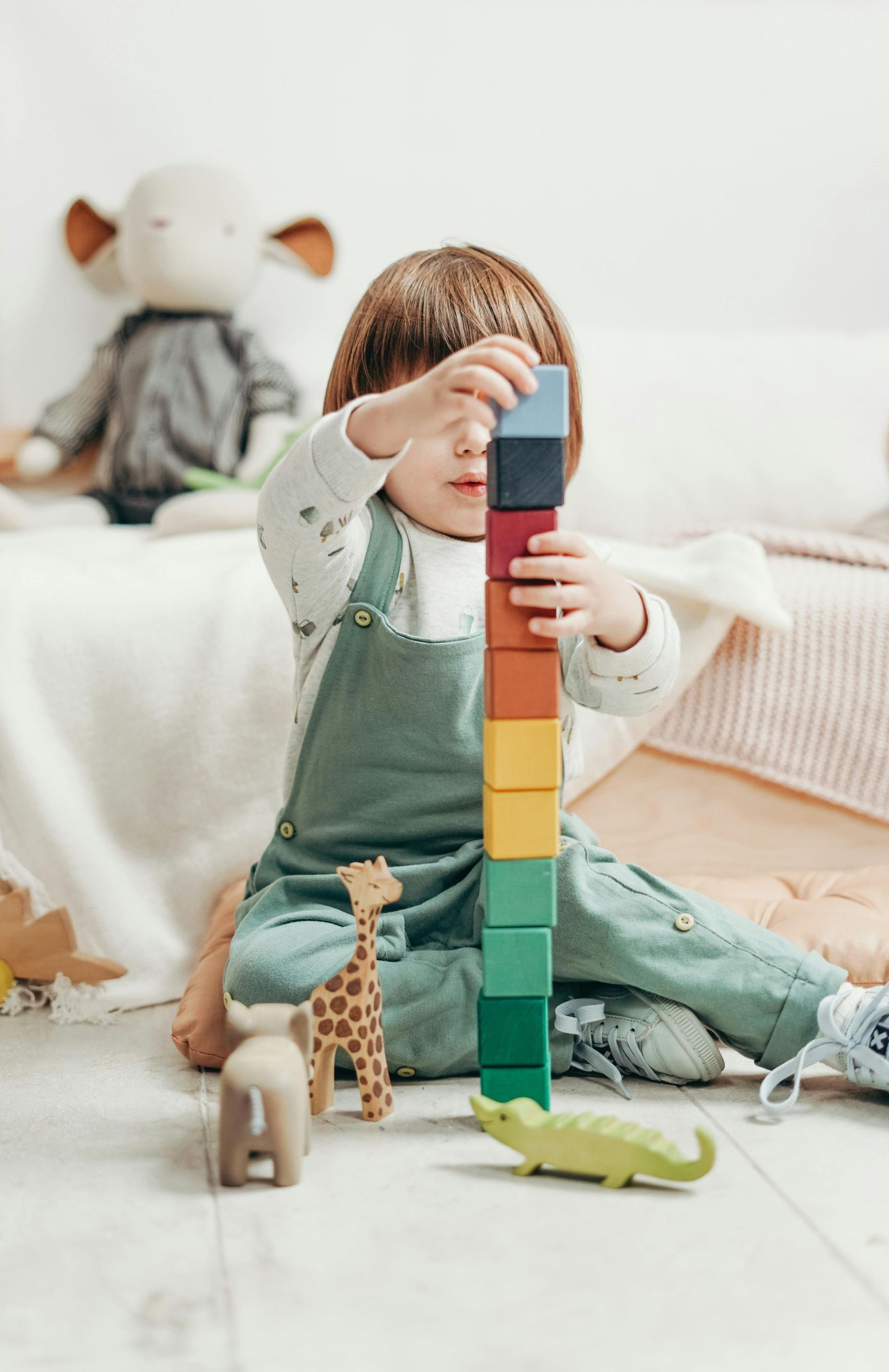 A little girl is sitting on the floor playing with wooden blocks.