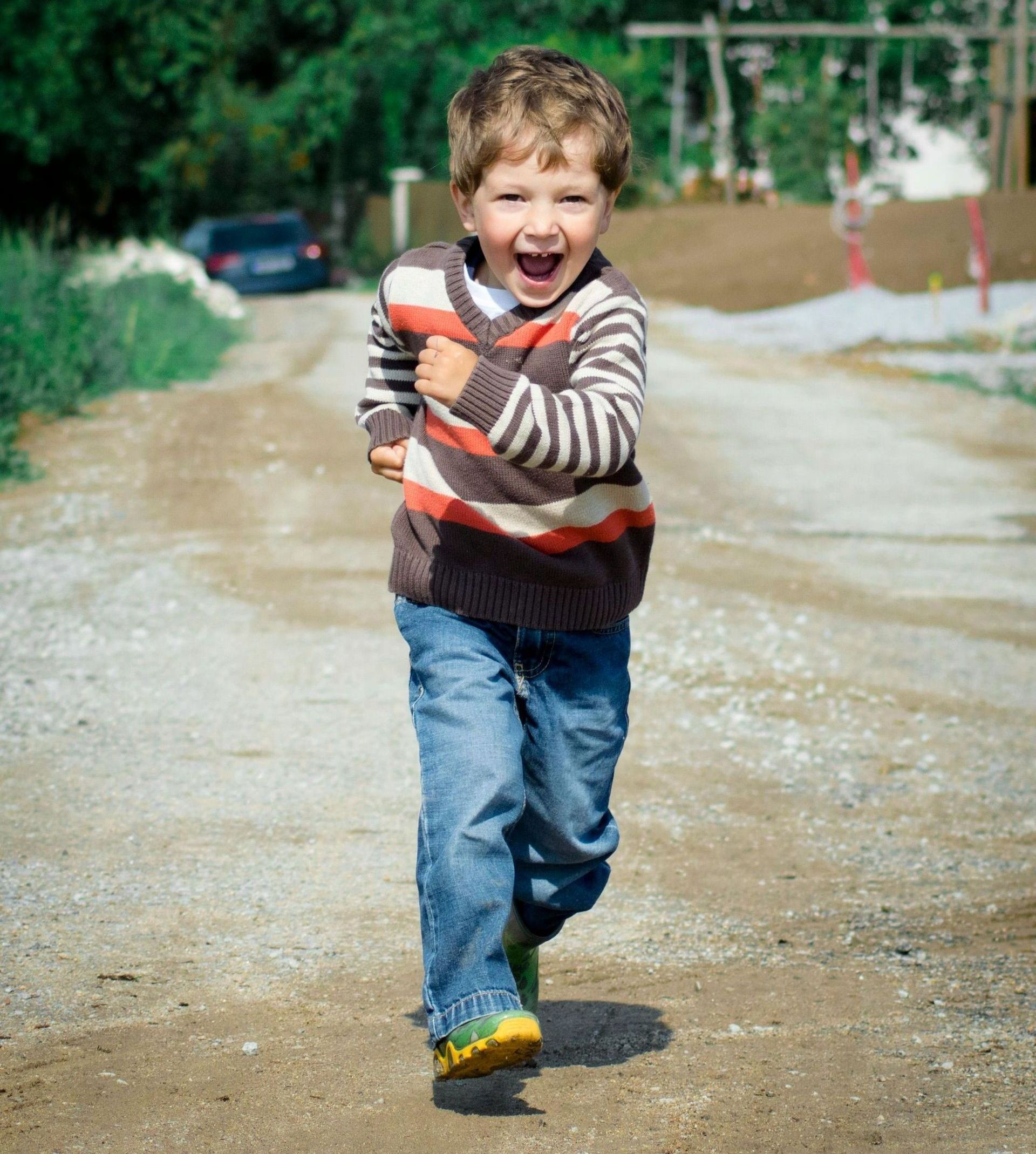 A young boy is running down a dirt road.