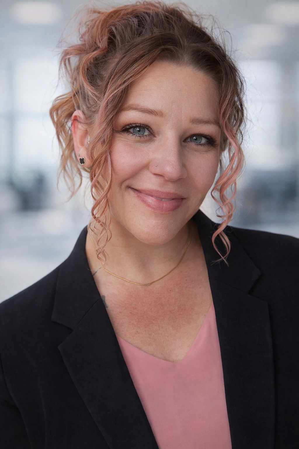 Woman with dark hair smiling, wearing a pink polo shirt with a logo.