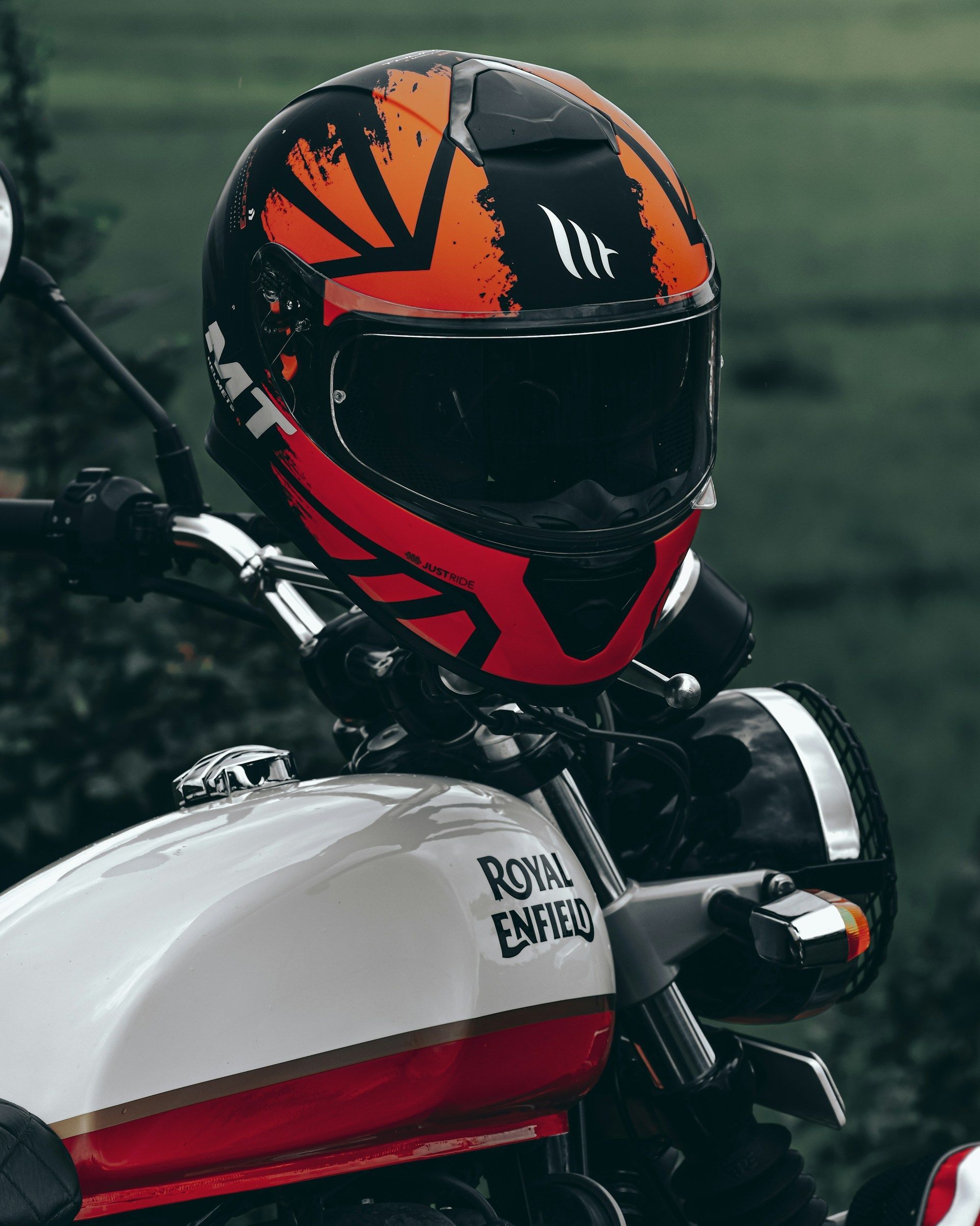 Motorcycle helmet with orange and black design on a Royal Enfield motorcycle.