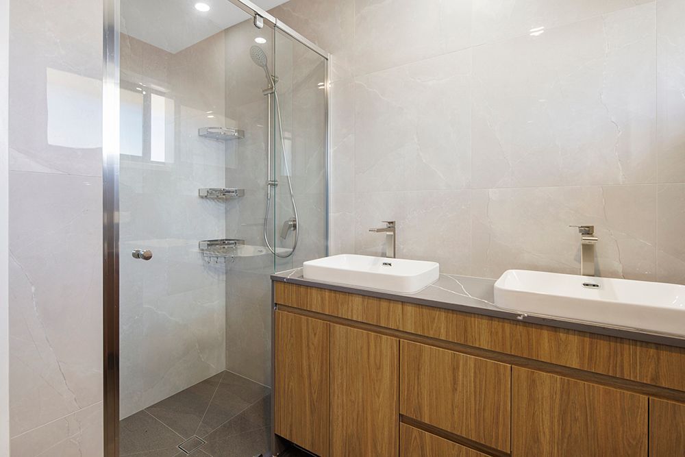 A bathroom with two sinks and a walk in shower.