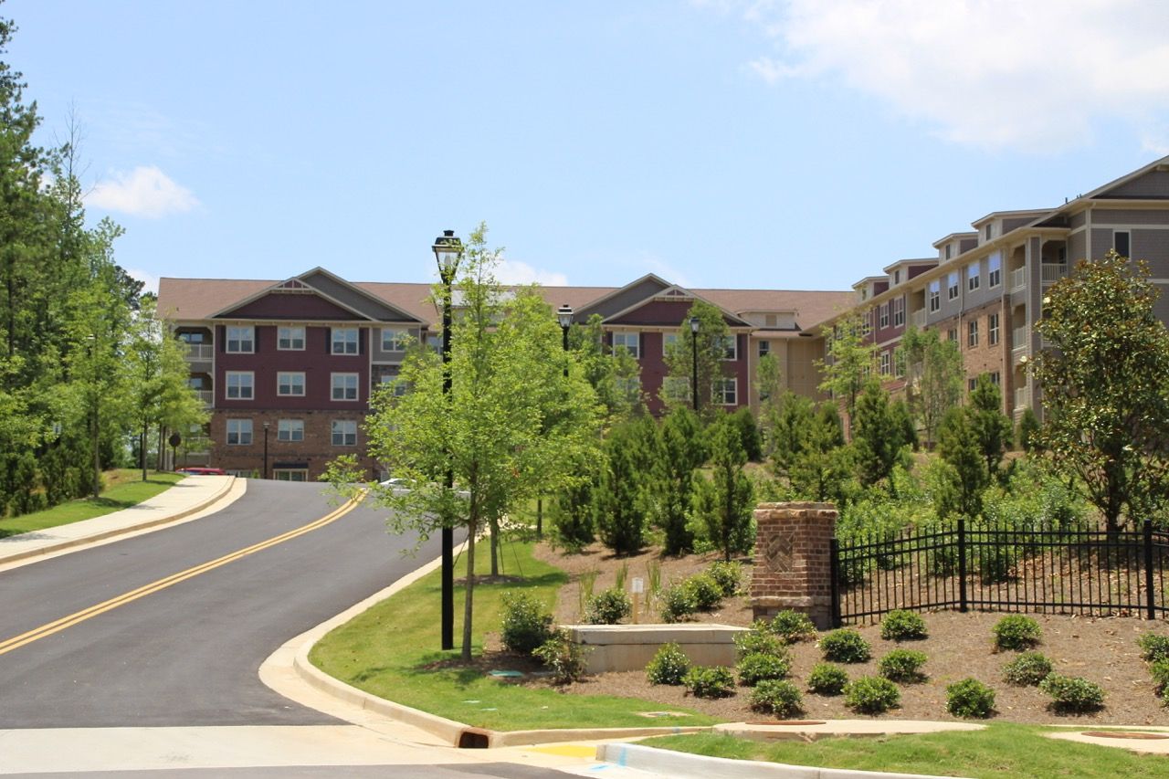 Exterior view of a multi-building apartment community with a curved street and landscaped grounds.