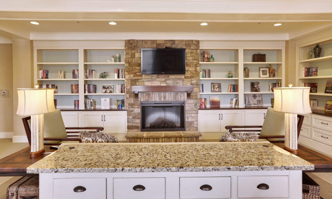 Communal lounge with granite island, stone fireplace, and built-in bookshelves.