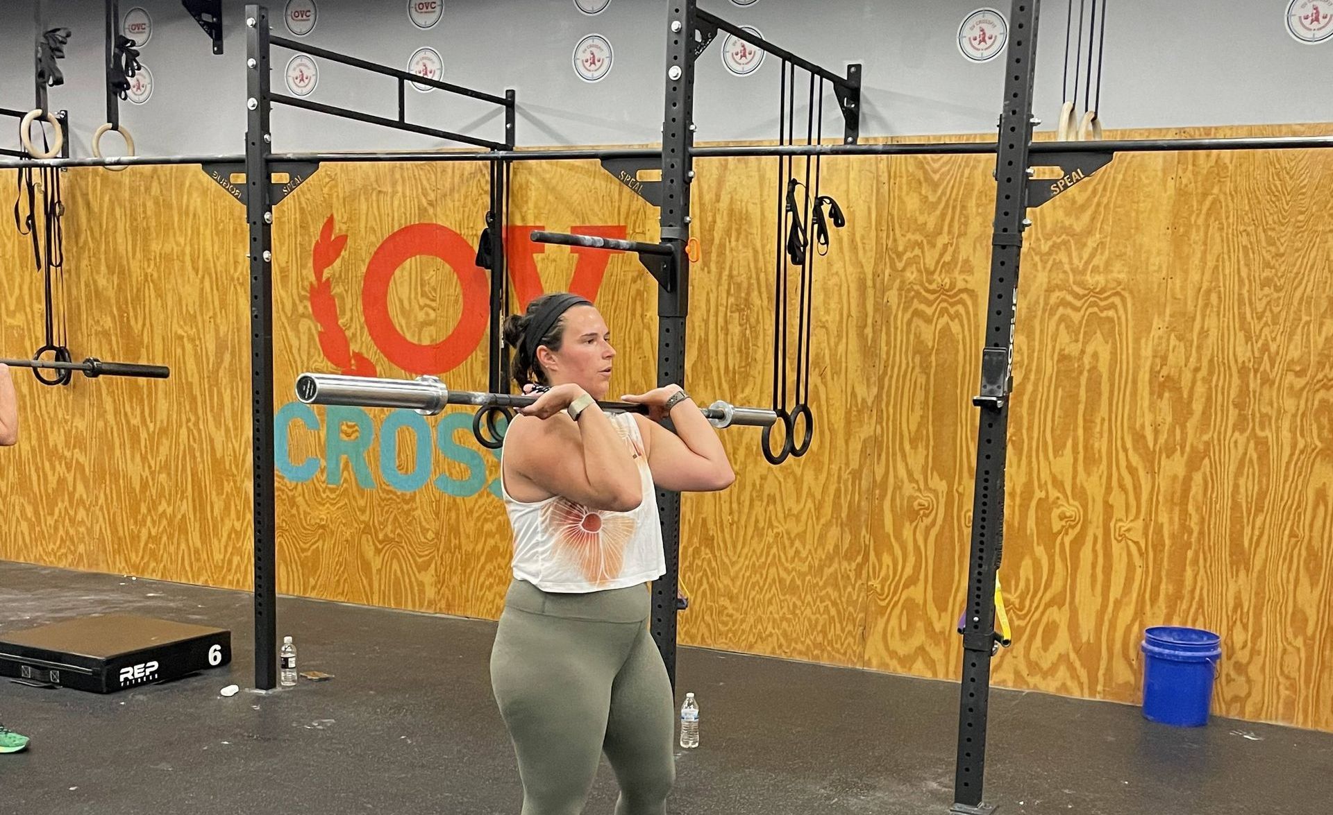 A woman is lifting a barbell in a gym.