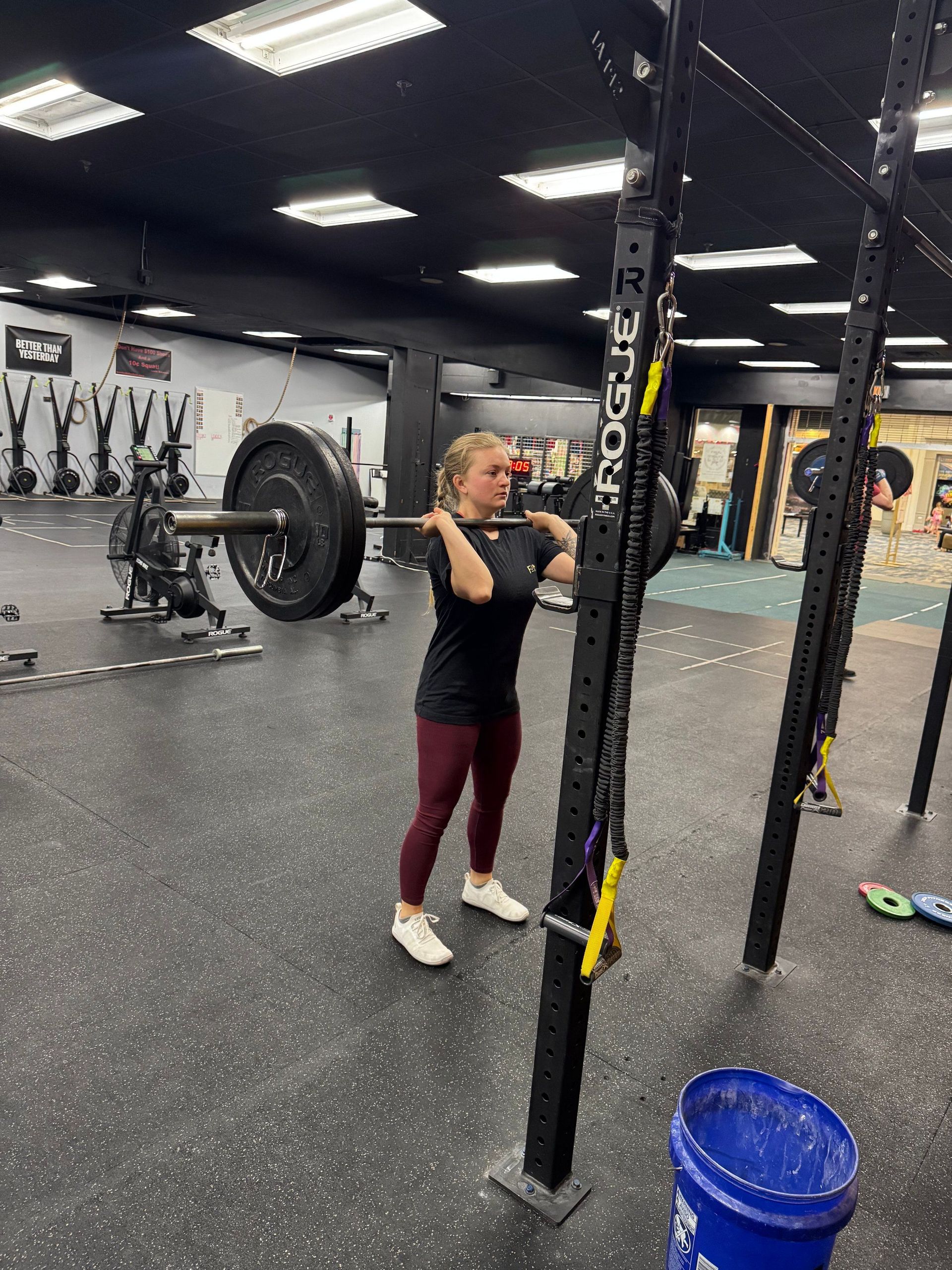 A woman is squatting with a barbell in a gym.