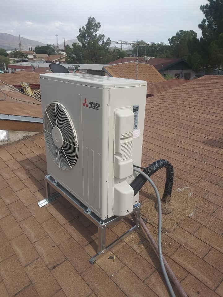 Mitsubishi AC unit on a rooftop, supported by a metal stand, connected by black tubing.