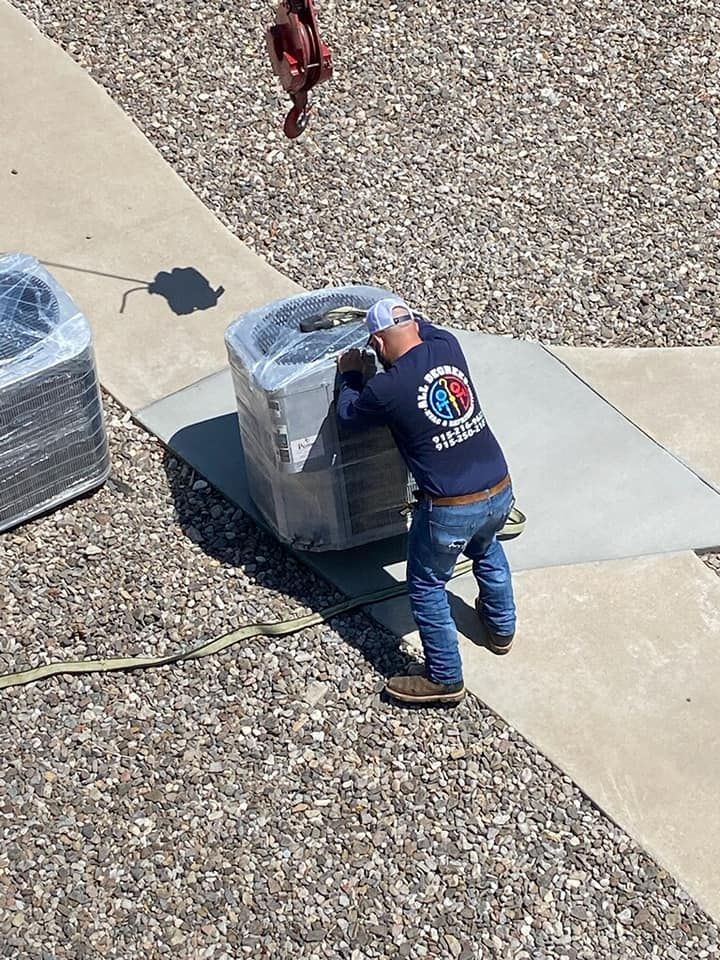 HVAC worker on a rooftop installing a wrapped air conditioner. A crane lifts the unit.