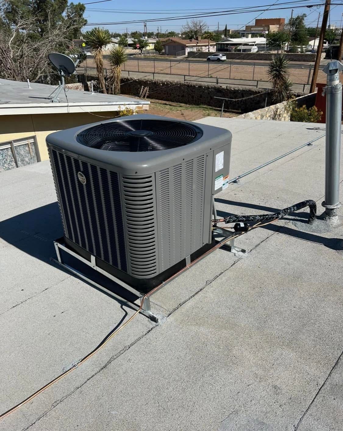 Gray air conditioning unit on a flat roof, viewed outdoors on a sunny day.