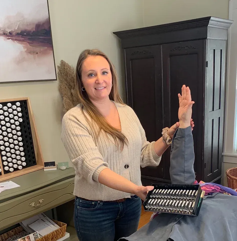 Woman holding a tool kit and person’s arm, possibly demonstrating a procedure; interior room with cabinet.