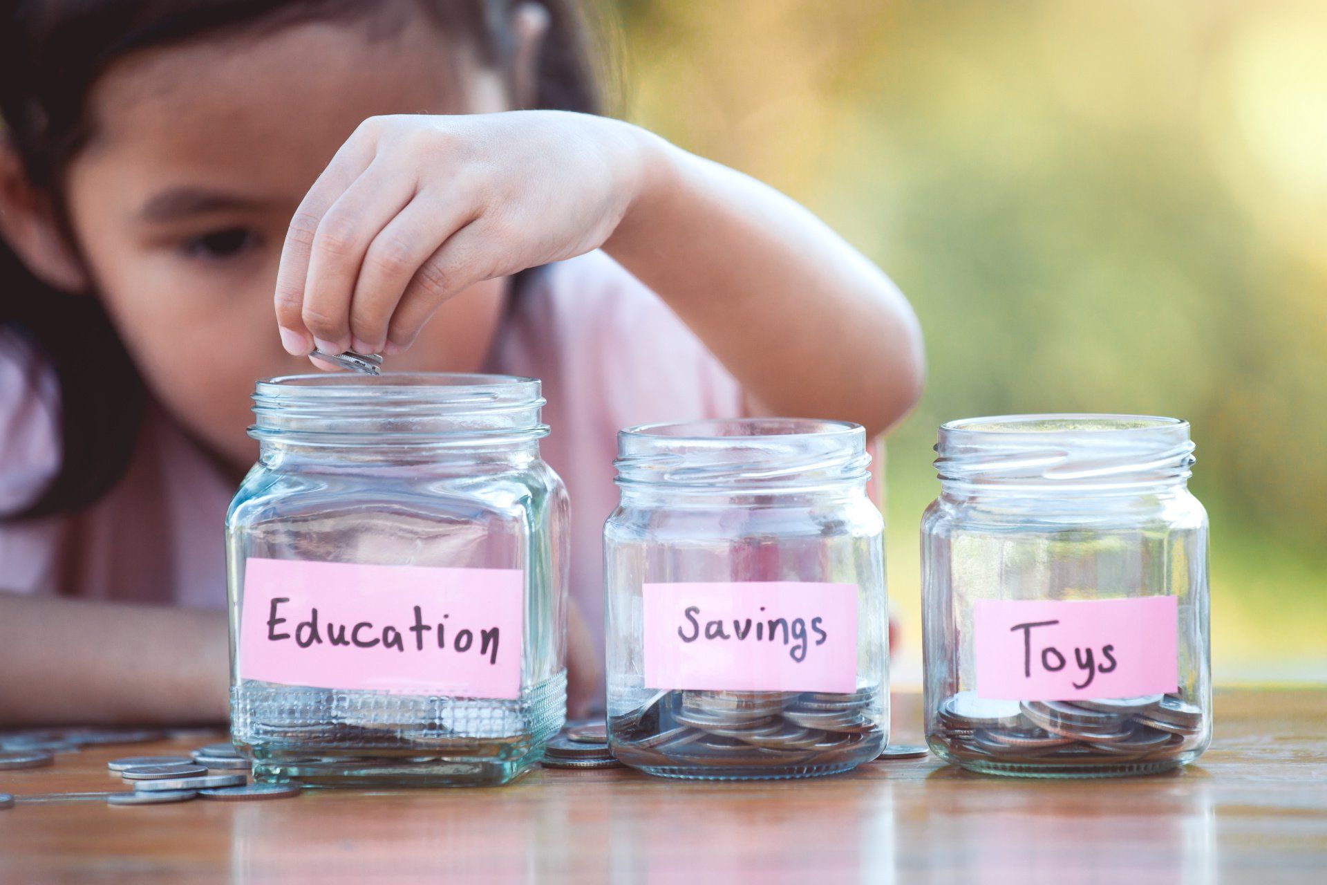 little girl with education, savings and toys jars