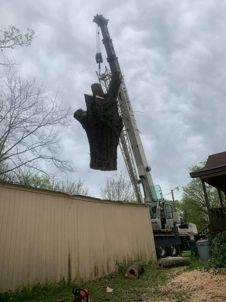 Crane lifting a large black object beside a beige building under a cloudy sky